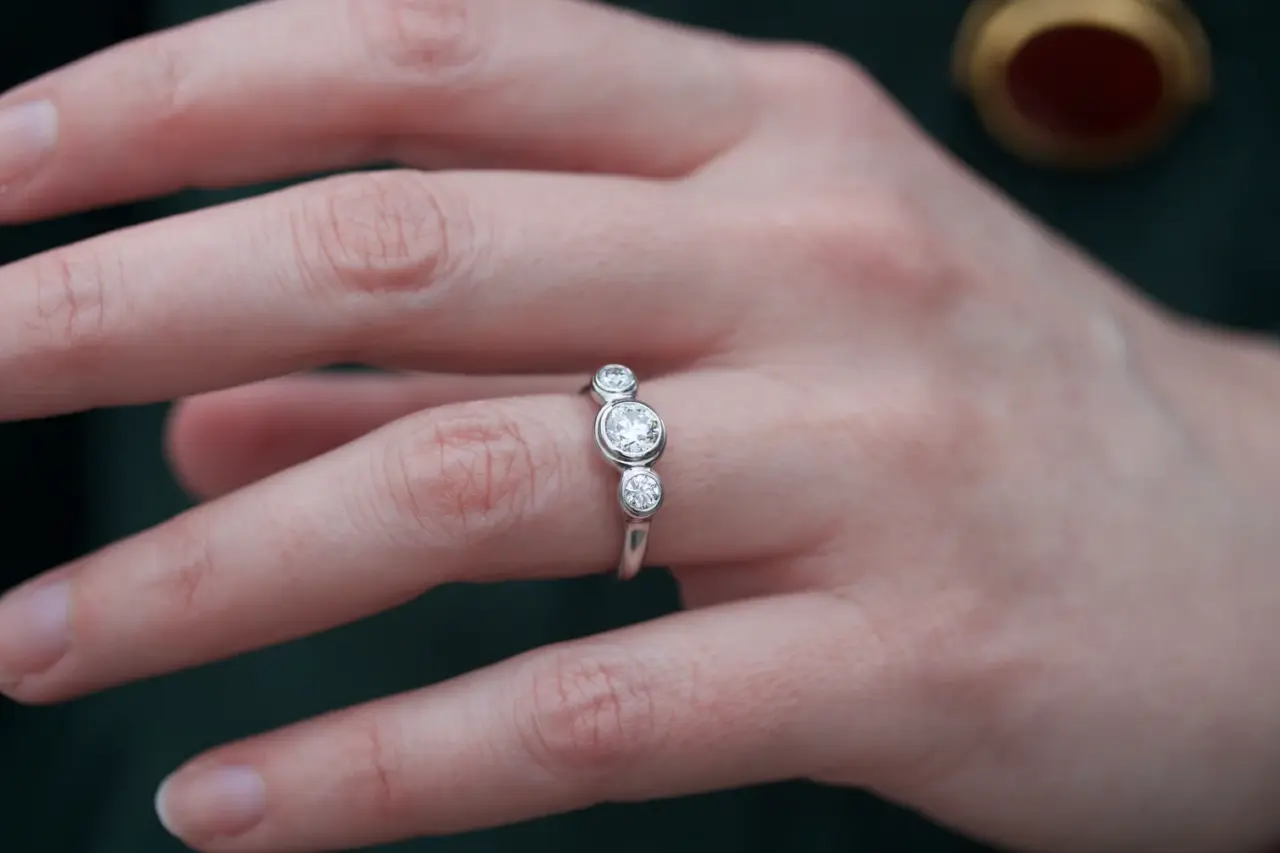 Close-up of Caleb Meyer Studio's three-stone engagement ring showcasing the bezel-set round brilliant diamonds in a sleek platinum band