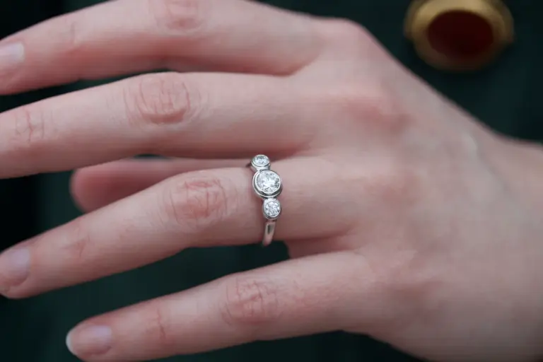 Close-up of Caleb Meyer Studio's three-stone engagement ring showcasing the bezel-set round brilliant diamonds in a sleek platinum band