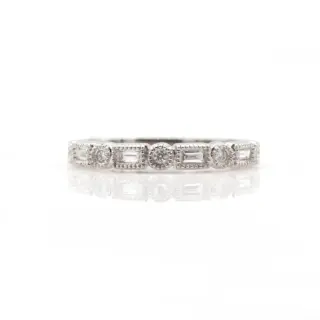 Close-up of a delicate 14 karat white gold stackable band featuring a vintage-inspired design. The ring is adorned halfway around with alternating round brilliant-cut diamonds totaling .17 carats, set within a milgrain-edged bezel that adds texture and antique charm.