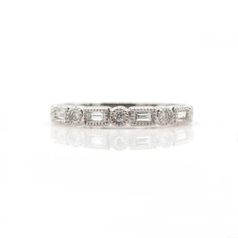 Close-up of a delicate 14 karat white gold stackable band featuring a vintage-inspired design. The ring is adorned halfway around with alternating round brilliant-cut diamonds totaling .17 carats, set within a milgrain-edged bezel that adds texture and antique charm.