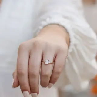 Elegant three‑stone engagement ring with emerald‑cut 1.0 ct moissanite and matching trillion‑cut accent stones on gold band