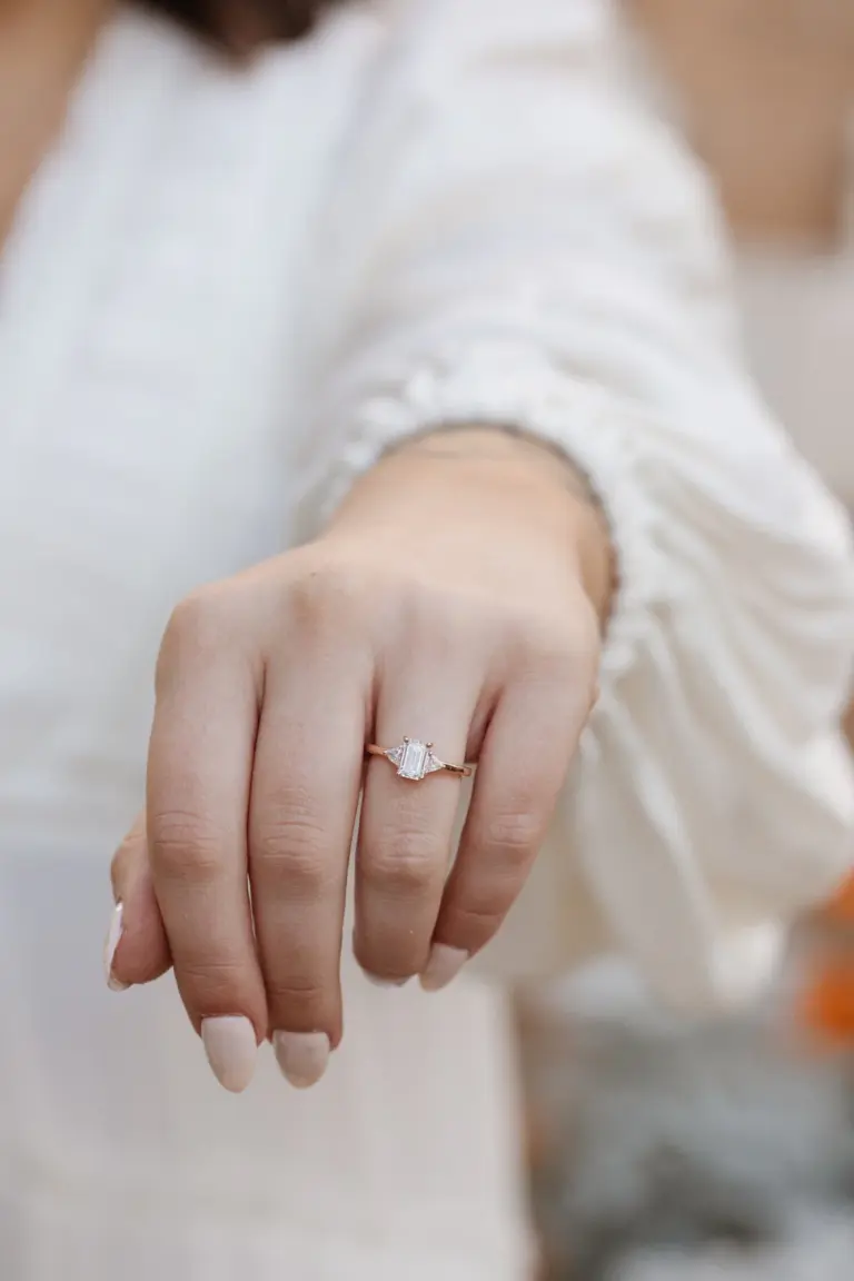 Elegant three‑stone engagement ring with emerald‑cut 1.0 ct moissanite and matching trillion‑cut accent stones on gold band