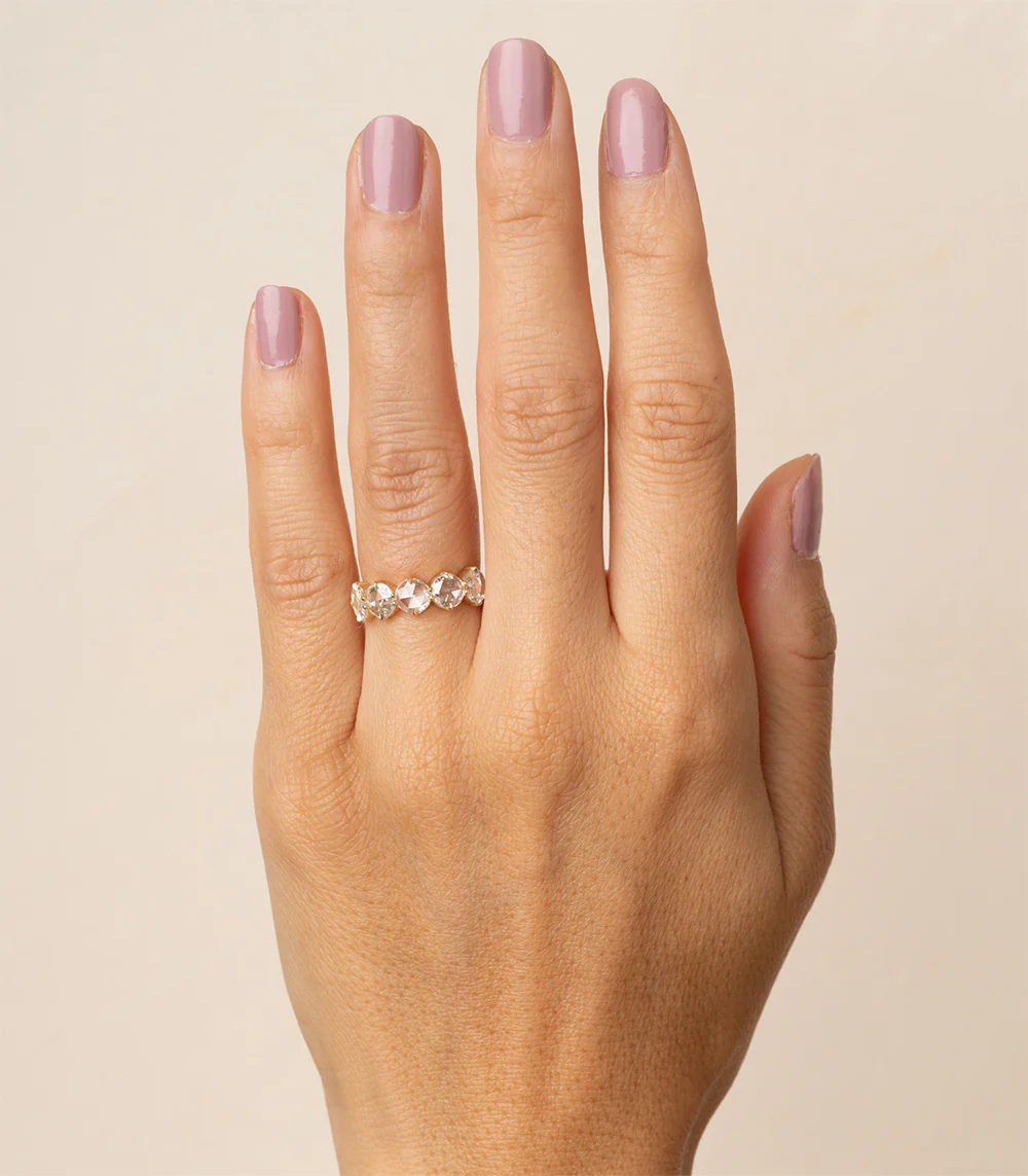 Close-up of textured yellow gold wedding band with five rose‑cut diamonds set with milgrain edging and subtle dark rhodium accents
