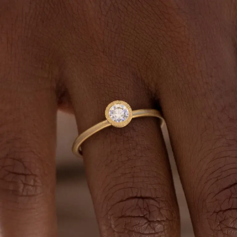 Close-up of Audry Rose's 18k Brushed Bezel Diamond Solitaire Ring showcasing the unique golden brushstroke bezel setting