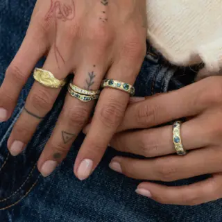 Elegant sapphire ring with deep blue stones lined halfway around a polished gold band, perfect for stacking or wearing solo