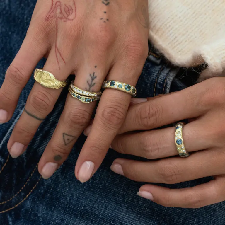 Elegant sapphire ring with deep blue stones lined halfway around a polished gold band, perfect for stacking or wearing solo