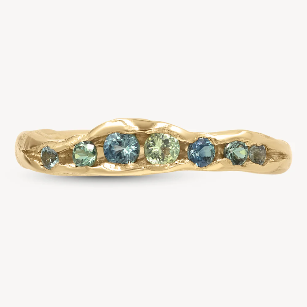Close-up of a 14k gold half eternity band featuring a row of round blue sapphires set in a sleek channel setting
