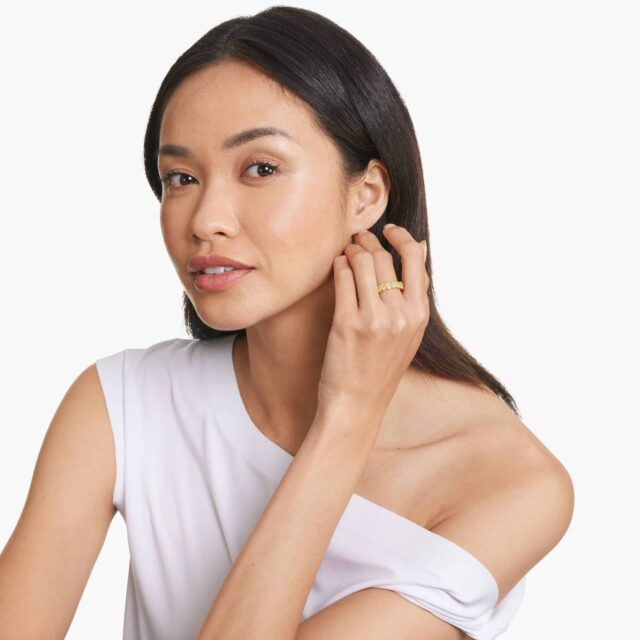 A woman shows off her newly placed gold diamond eternity engagement ring, celebrating a joyful and romantic proposal moment.