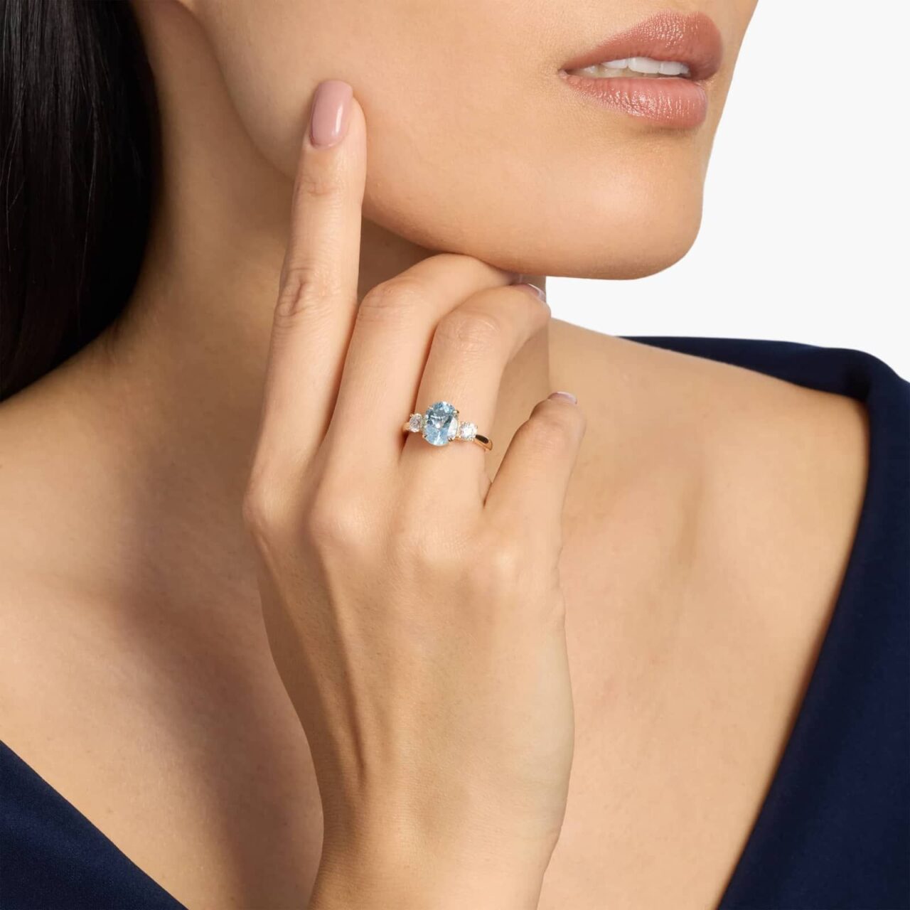 Oval-cut blue aquamarine engagement ring with diamond side stones in yellow gold