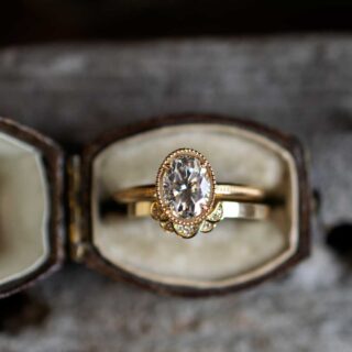 Hand wearing Marilyn Brogan’s 1.5 ct oval Art Deco diamond ring in yellow gold, showcasing elegant milgrain band and vintage-inspired geometric setting.