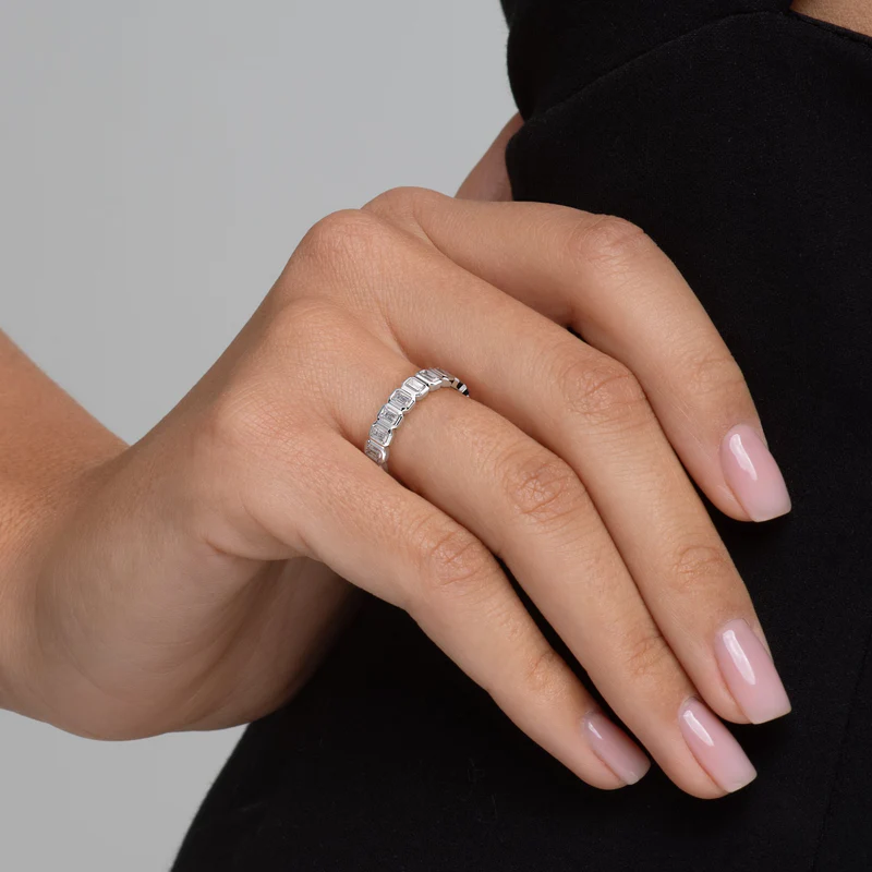 Sleek bezel eternity ring with emerald‑cut diamonds encircling a 14K white gold band
