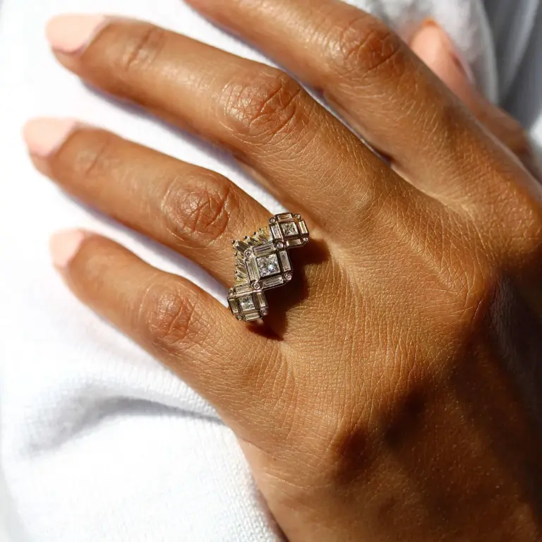 Close-up of The Darby ring showing princess-cut center diamond flanked by geometric halo set in 14K gold.