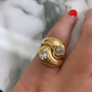 Close-up of Brent Neale's Knot Ring showcasing two heart-shaped diamonds set in a polished 18K yellow gold knot design.