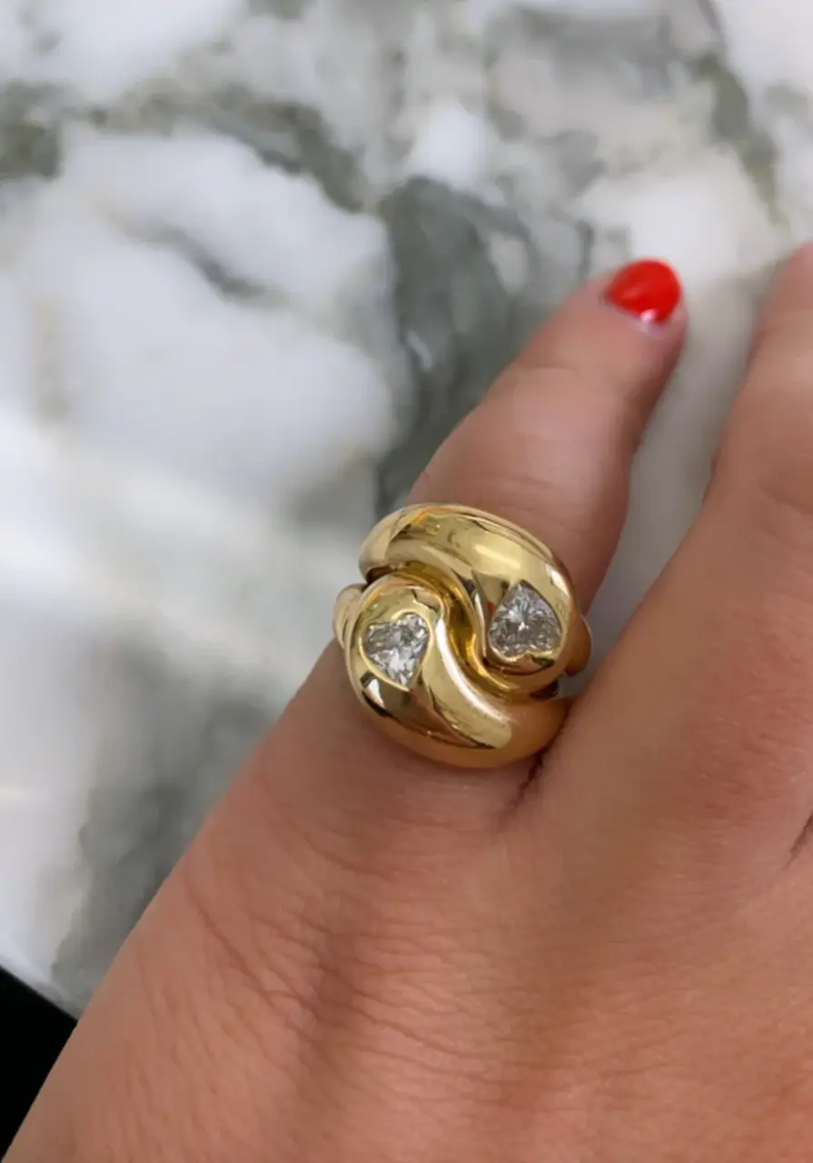 Close-up of Brent Neale's Knot Ring showcasing two heart-shaped diamonds set in a polished 18K yellow gold knot design.