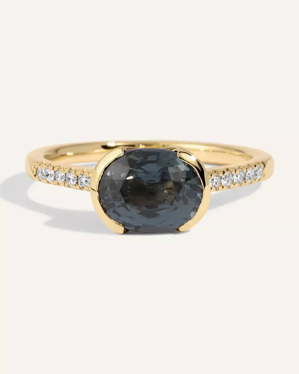 Detailed view of the Estrada Ring: a 2.31 ct dark gray‑blue spinel mounted side‑to‑side in a half‑bezel 14k gold setting, enhanced by a row of .09 ctw SI G‑H diamonds covering half the band