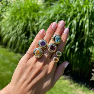 Close-up of Stephanie Gottlieb's Mini Candy Button Ring showcasing a polished 14K yellow gold band with a bold emerald gemstone and diamond accents