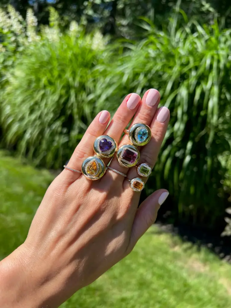 Close-up of Stephanie Gottlieb's Mini Candy Button Ring showcasing a polished 14K yellow gold band with a bold emerald gemstone and diamond accents