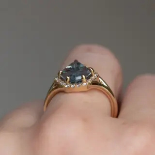 Anueva Jewelry's 2.34ct fantasy cut carved shield Montana sapphire ring in 14k yellow gold displayed on a stand, emphasizing its luxurious design and craftsmanship