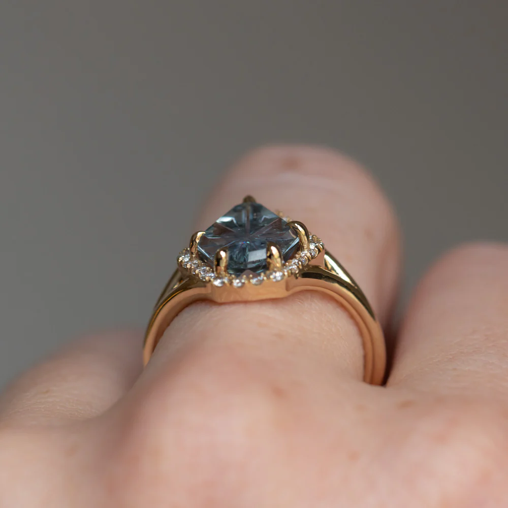 Anueva Jewelry's 2.34ct fantasy cut carved shield Montana sapphire ring in 14k yellow gold displayed on a stand, emphasizing its luxurious design and craftsmanship