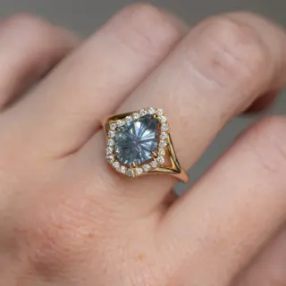 Model wearing Anueva Jewelry's 2.34ct fantasy cut carved shield Montana sapphire ring in 14k yellow gold, showcasing its unique design and radiant gemstone