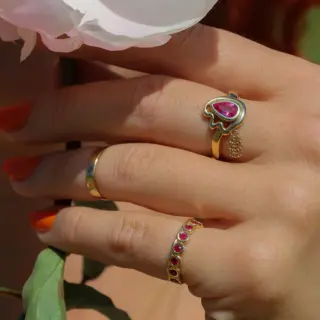 Gold ring with pink sapphire and dangling gold chain tassels.