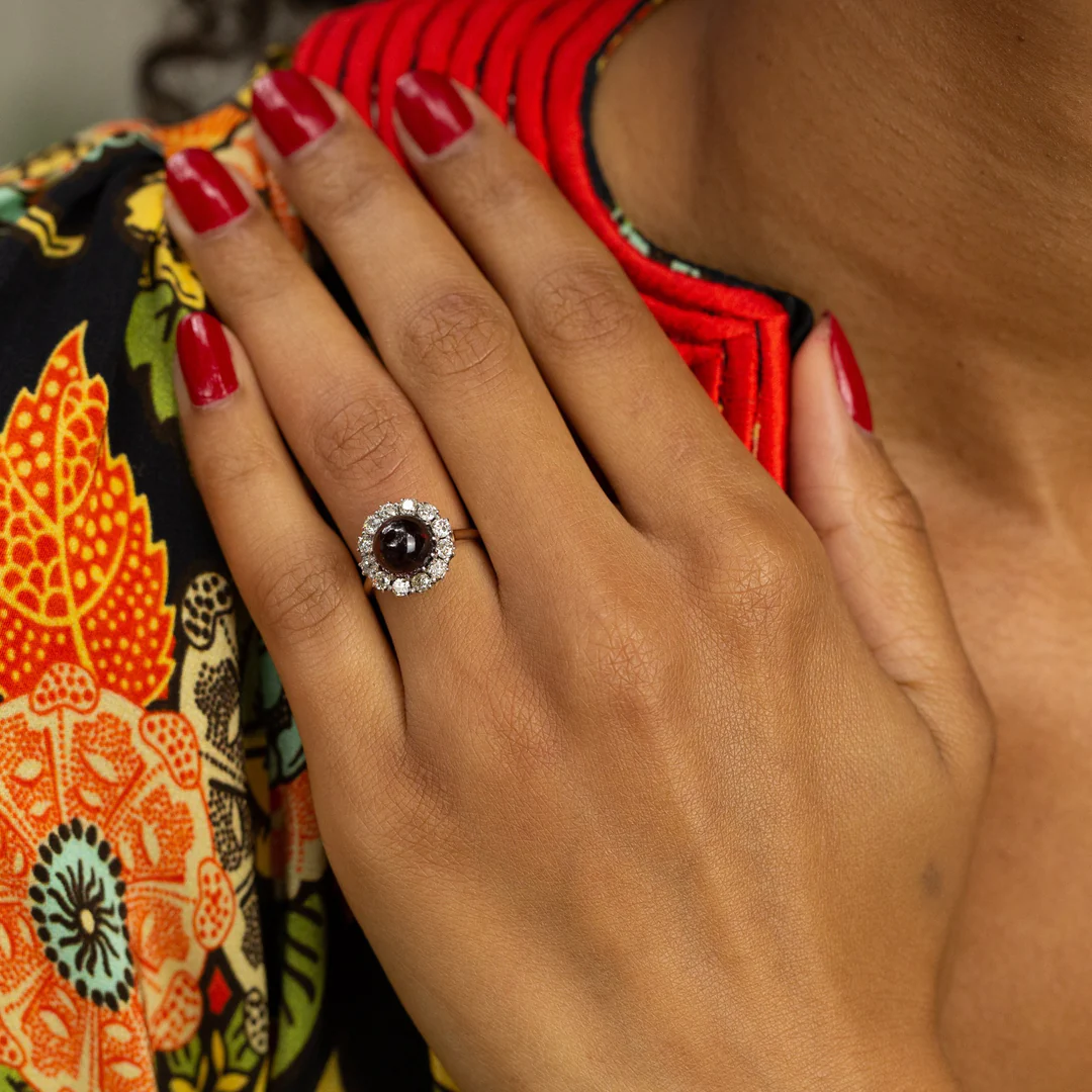 Vintage ring with glowing garnet cabochon and a diamond halo of 12 Old‑Mine‑cut stones set in two‑tone sterling silver and yellow gold
