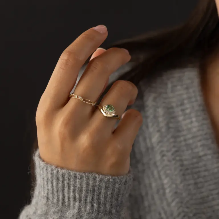 Model wearing the Astronomer Ring, showcasing its mint green garnet and delicate orbit of diamonds on the finger.