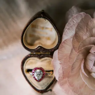 Antique pear-shaped diamond engagement ring with ruby halo and diamond-accented shoulders, circa 1900, handcrafted in platinum and 18kt yellow gold