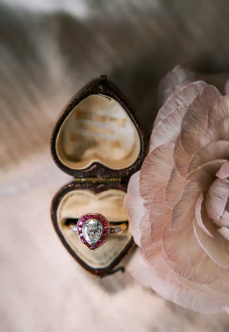 Antique pear-shaped diamond engagement ring with ruby halo and diamond-accented shoulders, circa 1900, handcrafted in platinum and 18kt yellow gold