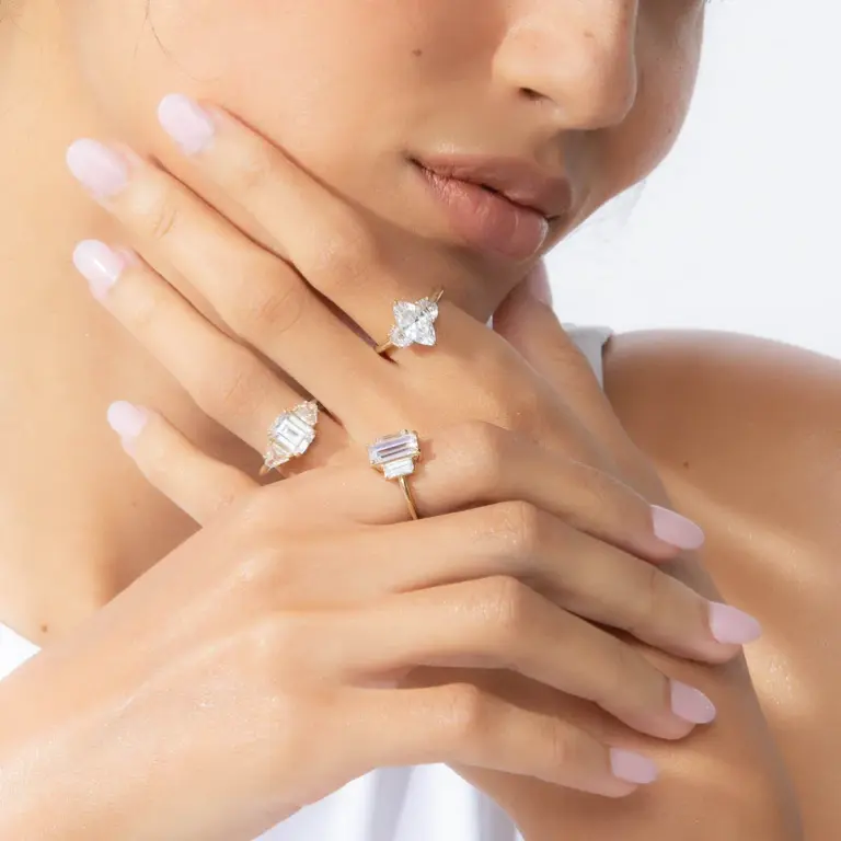 Side view of Shahla Karimi trilogy ring with flush emerald‑cut center and geometric triangle accents.