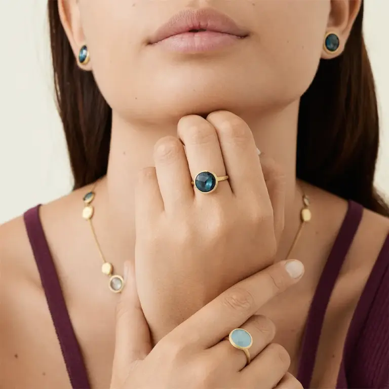 Close-up of Marco Bicego Jaipur ring showcasing a radiant London blue topaz set in 18K yellow gold with intricate Florentine hand-engraving.