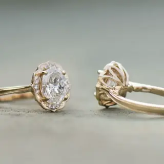 Side view of Daisy Blossom engagement ring with daisy petal under-gallery, vintage-style milgrain, and oval-cut center diamond