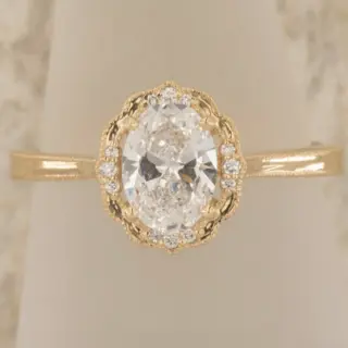 Daisy Blossom 14k yellow gold oval diamond ring displayed with focus on milgrain detailing, floral bracket, and brilliant-cut accents