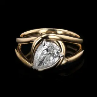 Orianne Jewelry's 1.54 carat pear diamond knot ring displayed on a stand, emphasizing its luxurious design and fine craftsmanship