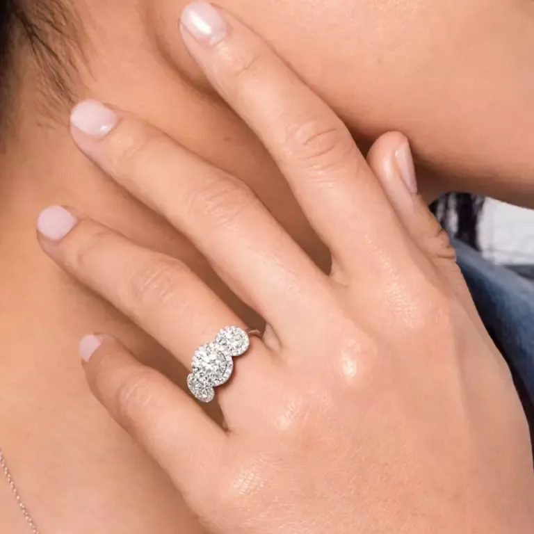 Side view of VRAI three‑stone halo engagement ring in yellow gold, highlighting the pavé halo and sleek band