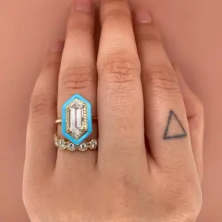 Close‑up: 1.5 ct white topaz center flanked by sparkling diamonds, encircled by pale‑blue enamel on delicate gold Yadira ring