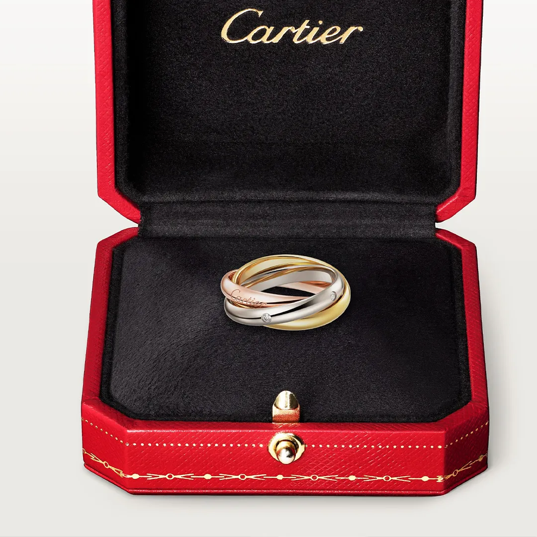Side view of Cartier Trinity ring highlighting the fluid interlocking 18k gold bands and sparkle of the diamonds.