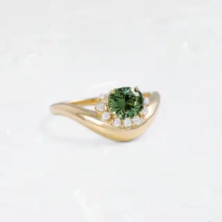 Top-down view of the Astronomer Ring highlighting the mint green demantoid garnet and the tenth hidden diamond beneath the setting.