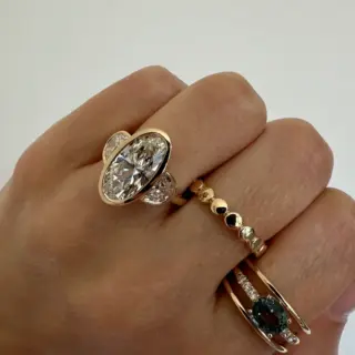 Orianne Jewelry three‑stone ring with a 3 ct oval lab‑grown diamond and half‑moon side stones in a yellow gold bezel setting