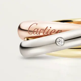 Model wearing the Cartier Trinity ring classic model with mixed‑metal bands and diamond accents on finger.