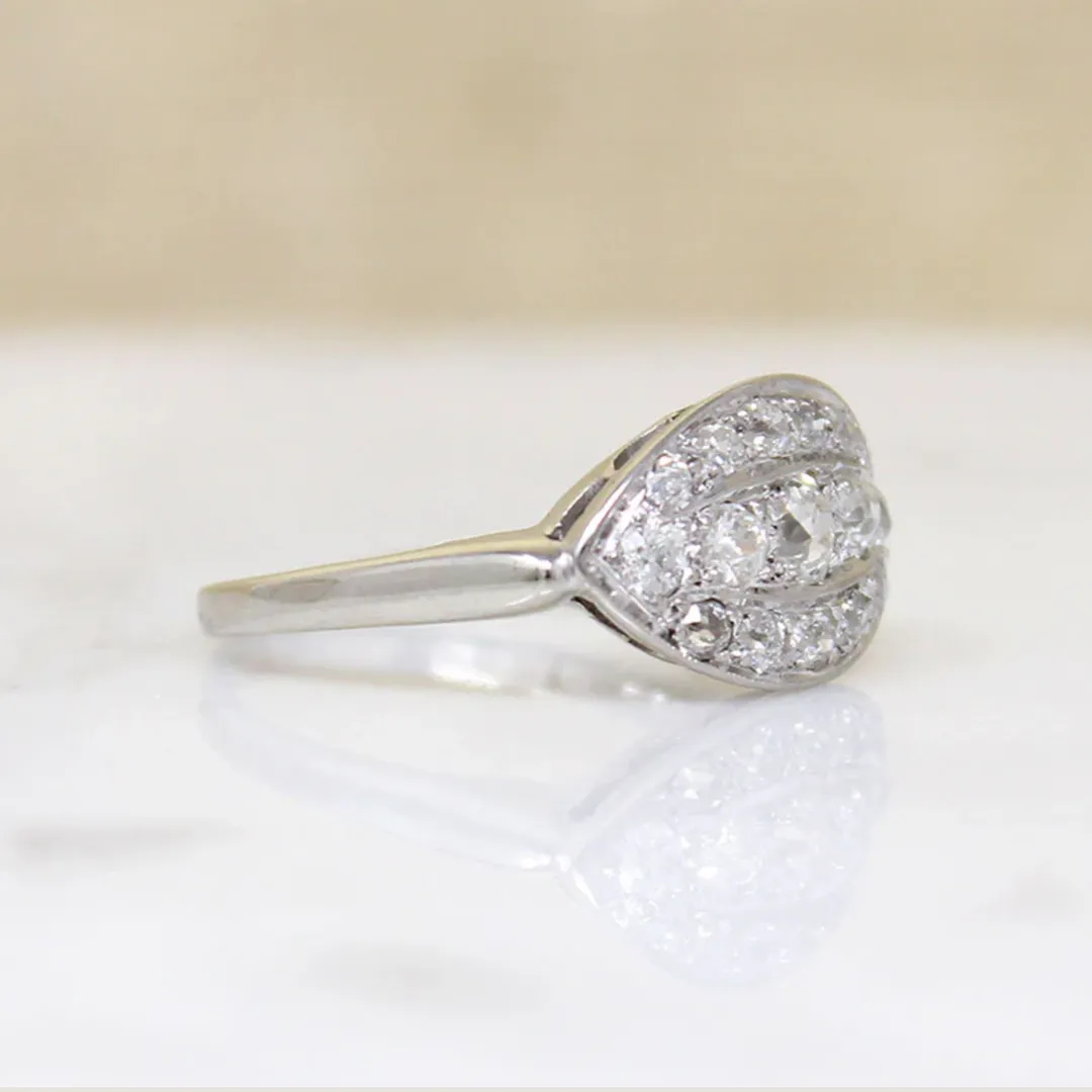 Close-up of Art Deco ‘Eye’ ring showcasing three graduated old-cut diamonds framed by a halo of smaller stones in a curved white gold setting