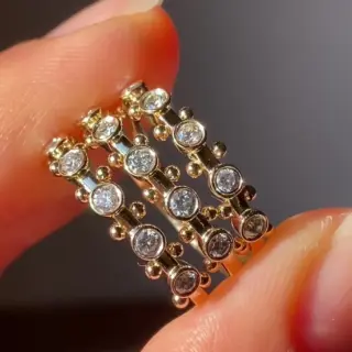 M. Hisae Koemi Ring displayed on a stand, with five post‑consumer white diamonds set along a 1.6 mm recycled‑gold band and signature golden beads between stones