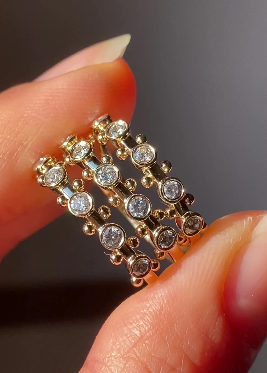 M. Hisae Koemi Ring displayed on a stand, with five post‑consumer white diamonds set along a 1.6 mm recycled‑gold band and signature golden beads between stones