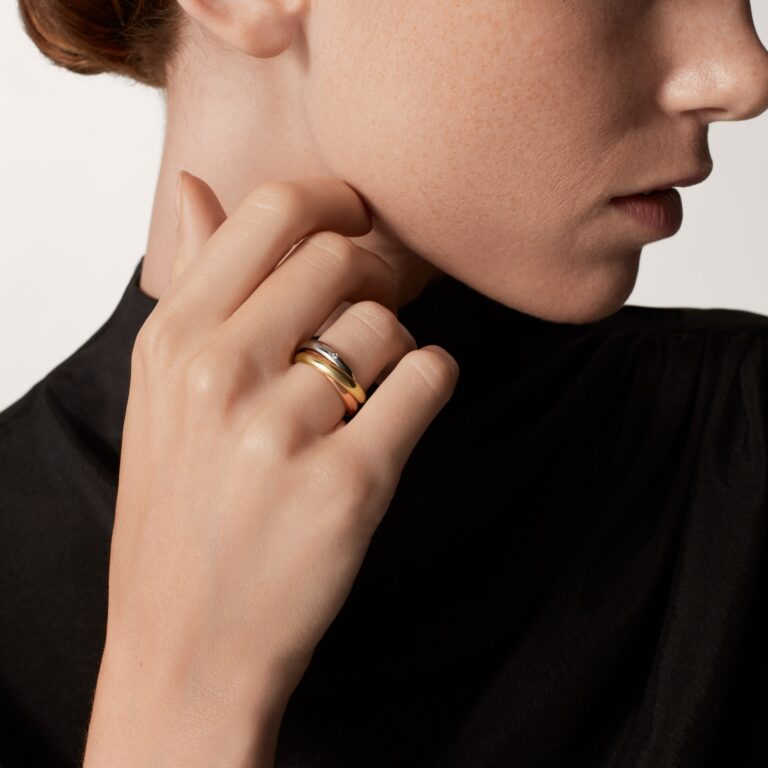 Close-up of Cartier Trinity 5‑diamond ring showing the delicate bezel‑set diamonds across the white gold band.