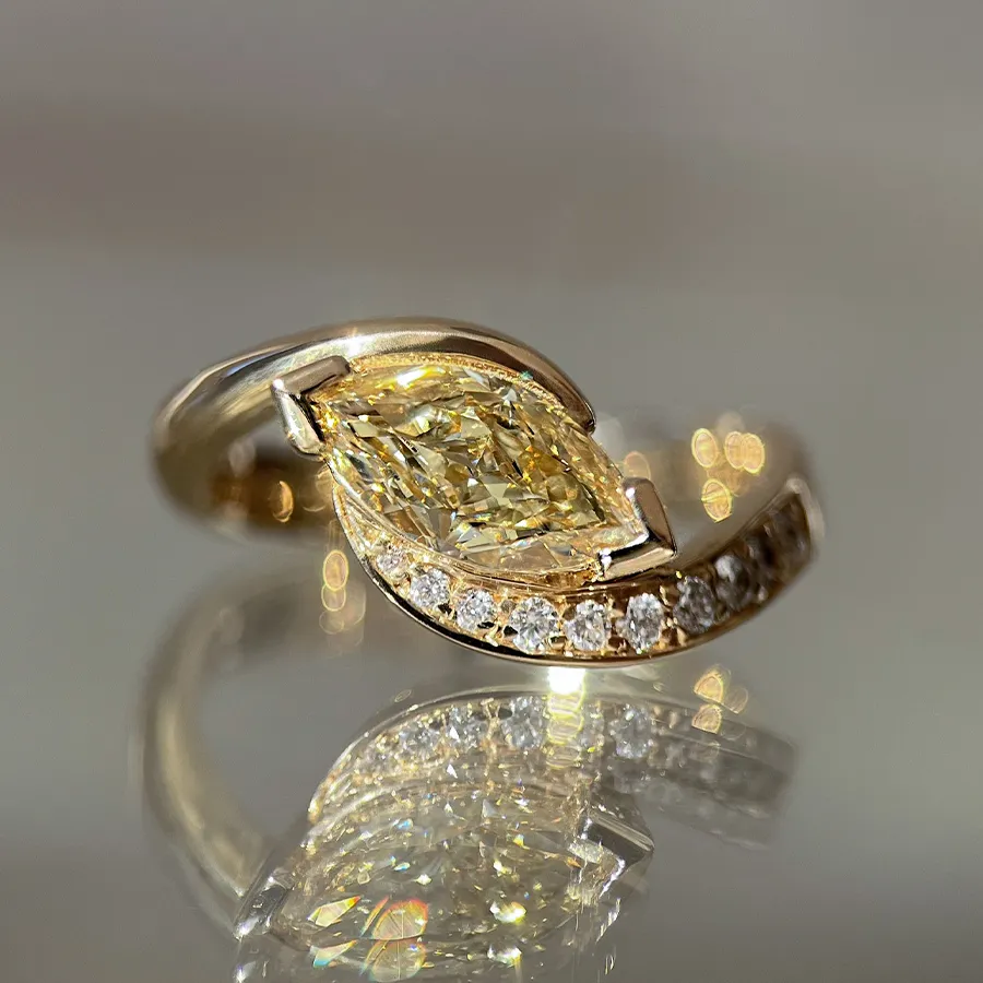 Close-up of 1.15ct yellow diamond marquise ring with demi pavé setting in 14k gold