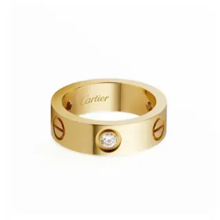 Close‑up of Cartier Love ring in yellow gold, highlighting three bezel‑set brilliant diamonds and polished, oval‑shaped band