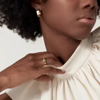 Side view of the Cartier Classic Love Ring in yellow gold with three sparkling diamonds embedded in iconic screw design