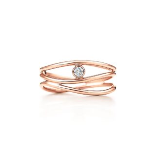 Close‑up of Elsa Peretti Wave ring in 18 kt rose gold, showing undulating triple bands cradling a small round brilliant diamond.