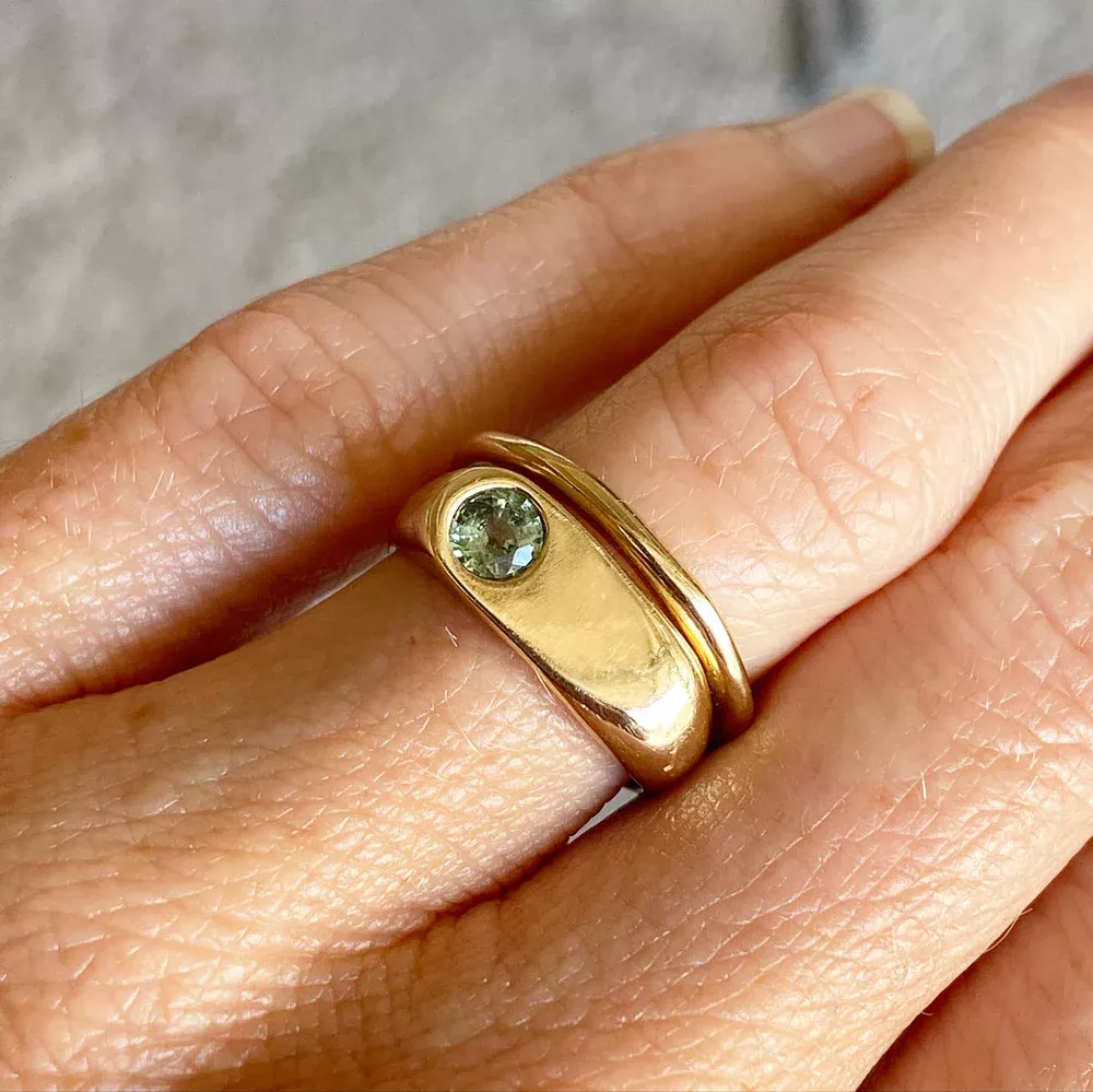 Close-up of the Indigo Emerald Ring, highlighting the intricate bezel setting and the sparkling emerald-cut center stone.