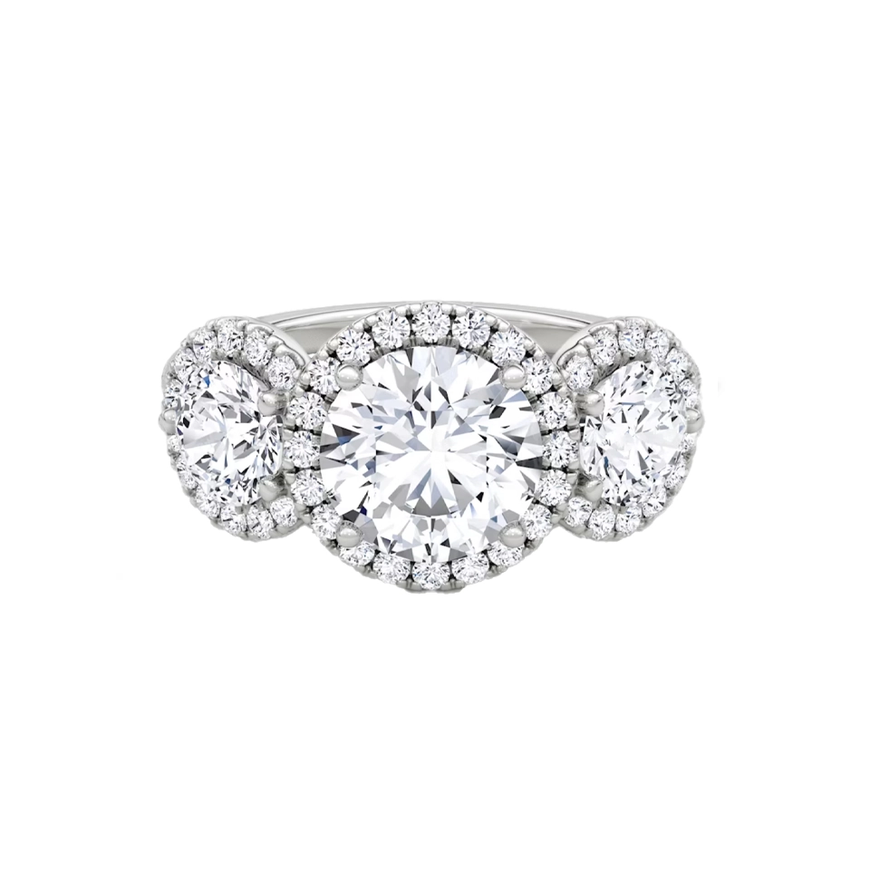 VRAI three‑stone halo ring on hand—featuring a round center diamond flanked by trapezoid side stones in yellow gold.
